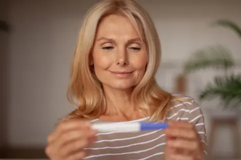 Bea Szenfeld, med ett leende, håller ett graviditetstest.