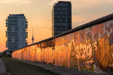 Zachód słońca nad graffiti na pozostałościach Muru Berlińskiego, przypominającego o tym, kiedy został zbudowany mur berliński.