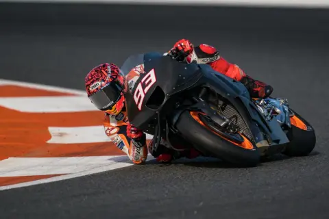 Piloto de MotoGP inclinado en curva, con su moto negra y naranja. La potencia de cuántos caballos tiene una MotoGP es asombrosa.