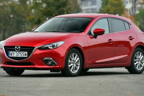Czerwona Mazda 3 2015 na parkingu, z widocznym numerem rejestracyjnym WY 3755W.