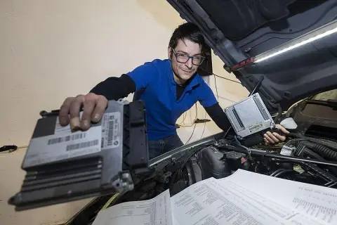 Técnico con gafas revisa unidades de control para modificaciones coche.