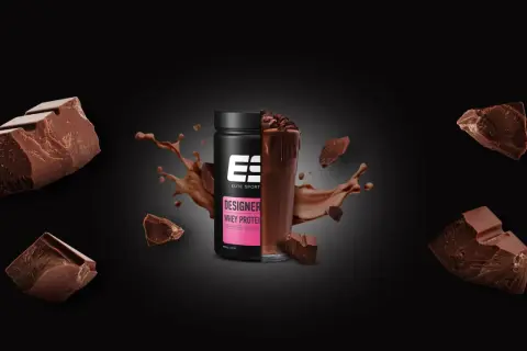 Schokoladenstückchen umgeben einen Becher Designer Whey Protein. Die Frage, ob Proteinpulver krebserregend ist, bleibt unbeantwortet.