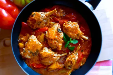 Un saporito pollo con peperoni in padella, con pezzi di pollo succulenti immersi in una ricca salsa rossa e verdure colorate.