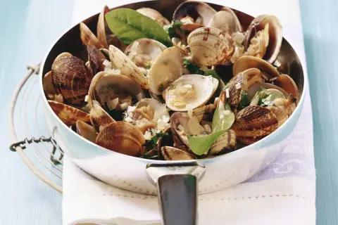 Frisch zubereitete vongole deutsch in einer Pfanne, garniert mit Kräutern und Knoblauch. Ein Genuss!