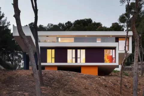 Casa moderna con voladizos y grandes ventanales, ideal para suelo rústico.