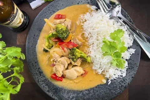 En smakrik thaigryta med kyckling, broccoli och paprika i en krämig sås, serverad med fluffigt ris.
