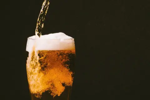 Birra dorata versata in un bicchiere, con schiuma abbondante e bollicine che salgono. Un piacere rinfrescante, ricco di sali minerali.