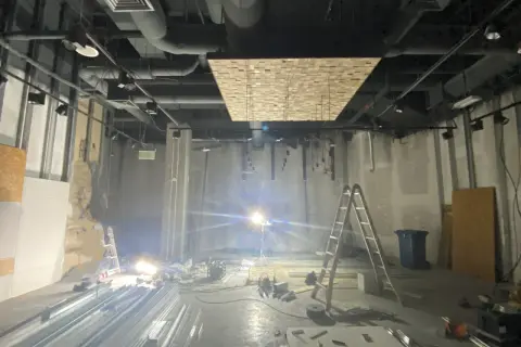 Wnętrze w remoncie z drabiną, materiałami budowlanymi i oświetleniem.