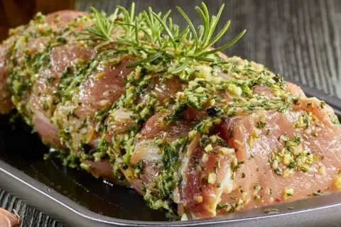 Schab w aromatycznej marynacie z czosnkiem i ziołami, gotowy do pieczenia.