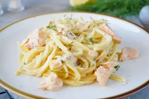 Spaghetti mit Lachs und Dill in cremiger Sauce auf einem Teller.