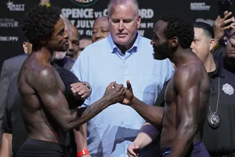 Terence Crawford and Errol Spence Jr. shake hands before their fight, surrounded by officials and a crowd.