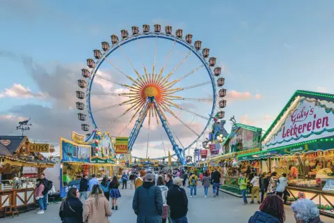 Buntes Treiben auf dem Frühlingsfest München mit Riesenrad, Essensständen und vielen Besuchern.
