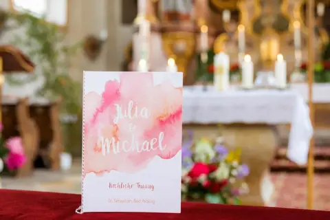 Hochzeitsprogramm für Julia & Michael. Im Hintergrund der Kirche erklingen bekannte kirchenlieder zum Mitsingen.
