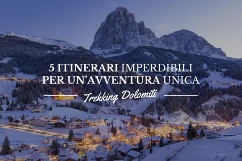 Paesaggio invernale con villaggio illuminato e montagne innevate. 5 itinerari imperdibili per un'avventura unica: Trekking Dolomiti.