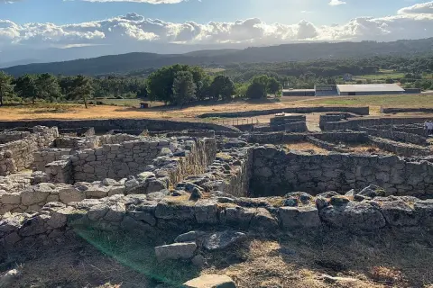 Ruinas de piedra en San Amaro, Ourense, bajo un cielo nublado y sol radiante.