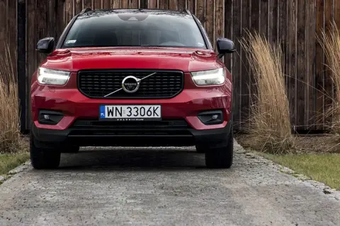 Czerwone Volvo XC40 na podjeździe. Zbliżenie na przód auta, gdzie widoczne są światła, grill i tablica rejestracyjna. Poznaj volvo xc40 wymiary.