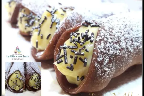 Cannoli siciliani con golosa crema al cioccolato, spolverati di zucchero a velo e granella scura. Un dolce irresistibile!