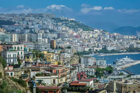 Panorama di Napoli con case colorate, il Vesuvio sullo sfondo e yacht nel porto. Come si dice in napoletano? "Napule è!