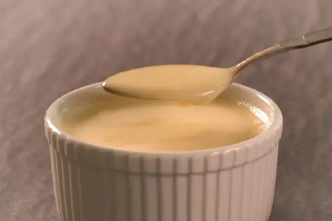 Cremige Vanillesauce, frisch zubereitet, auf einem Löffel. Perfekt zum vanillesauce selber machen.