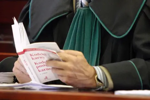 Prawnik w todze czyta Kodeks karny.