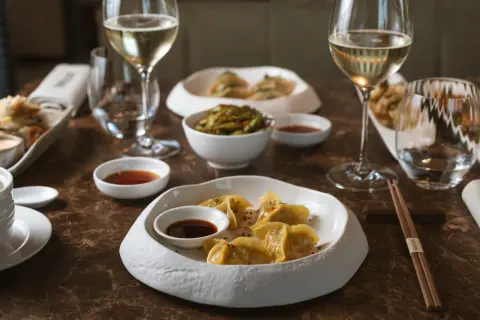 Ristoranti stellati Milano: un'esperienza culinaria con ravioli dorati, edamame e vino bianco.