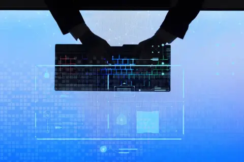 Dłonie w rękawiczkach piszą na podświetlanej klawiaturze, tworząc tło dla cyfrowego świata, gdzie czai się cyberprzestępczość.