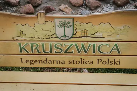 Drewniana ławka z napisem "Kruszwica Legendarna stolica Polski" i malowidłem nawiązującym do szlaku piastowskiego.