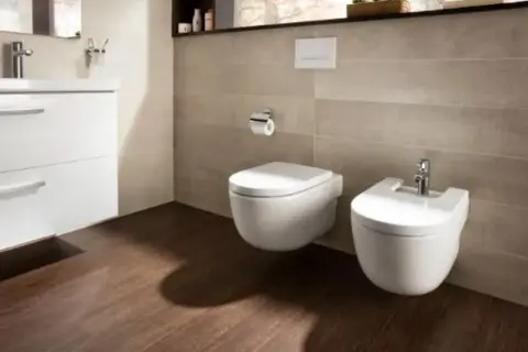 Nowoczesna łazienka z wiszącym wc i bidetem. Jest sporo miejsca na swobodne poruszanie się.
