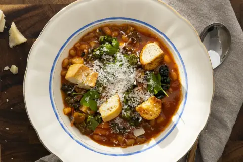 En mustig bönsoppa med grönsaker och krutonger, toppad med rikligt riven italiensk ost.