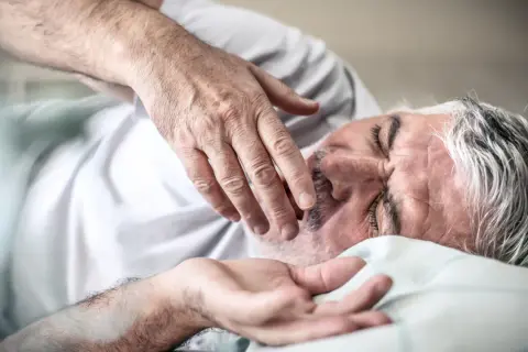 Starszy mężczyzna śpi, jego dłoń delikatnie dotyka twarzy. Może to być odpowiedź na pytanie, dlaczego starsi ludzie dużo śpią – potrzebują regeneracji.