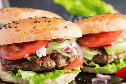 Pyszne burgery wołowe z pomidorem, ogórkiem i cebulą. Idealne, by pokazać, jak przyprawić mięso wołowe na burgery.