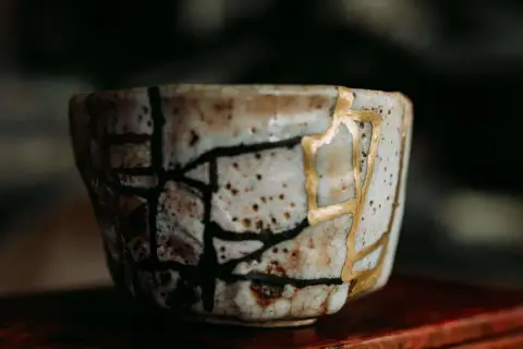 Zerbrochene Keramik, repariert mit Gold, symbolisiert die Kintsugi Psychologie: Narben machen uns stärker und schöner.