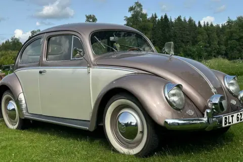 En tvåfärgad bubblan bil står på en gräsmatta.