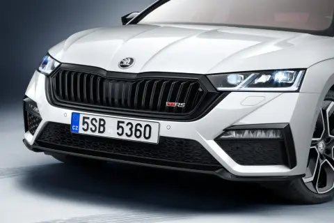 Biała Skoda Octavia 4 z czarnym grillem i czerwonym znaczkiem VRS. Zbliżenie na przednią część samochodu.