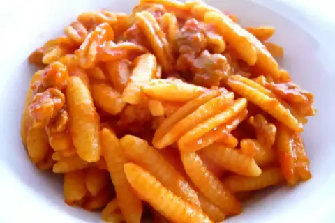 Malloreddus alla campidanese, pasta sarda con sugo di pomodoro e salsiccia, un piatto ricco e saporito.