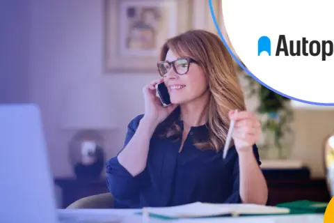 Kobieta w okularach rozmawia przez telefon, pracując przy laptopie. Rozwiązania autopay mobility ułatwiają jej codzienne życie.