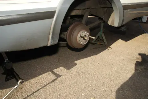 Bil lyfts med domkraft för att byta däck. Ett hjul är borttaget och bilen stöds av en pallbock.