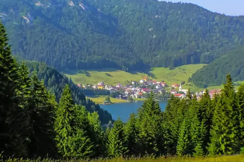 Idyllisches Dorf am See, umgeben von grünen Hügeln und Nadelwäldern. Perfekt für Slowakei Reisetipps!