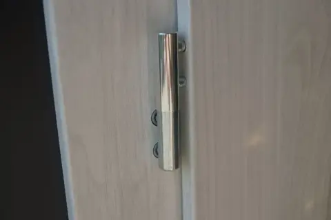 Metalowy zawias drzwiowy, widoczna regulacja zawiasów drzwi.
