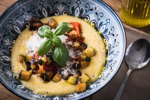 Cremige Polenta mit gebratenem Gemüse, Parmesan und Basilikum. Was ist Polenta? Ein herzhaftes Gericht aus Maisgrieß.