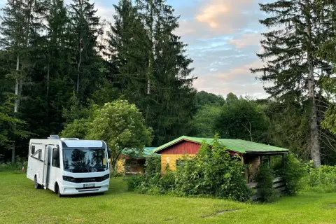 Wohnmobil neben bunten Hütten im Wald, ein idyllischer Ort nahe Banská Štiavnica.