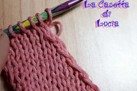 Uncinetto su ferri colorati, un lavoro a maglia rosa che ricorda un baktus.