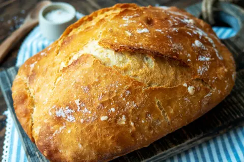 Ein frisch gebackenes, knuspriges Brot liegt auf einem Holzbrett. Perfekt für einfaches Brot backen.