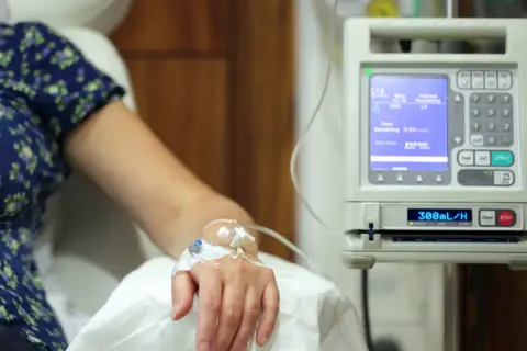 Pacjent otrzymuje kroplówkę, która może być lekiem na raka. Aparatura medyczna monitoruje przepływ płynu.