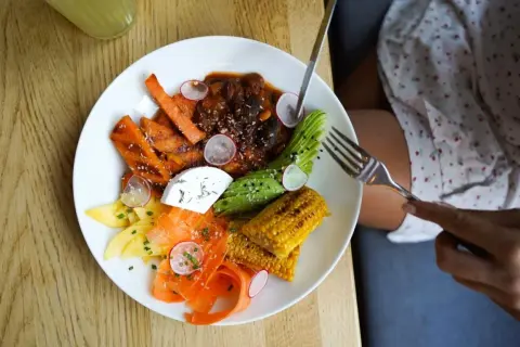 Assiette colorée avec carottes, avocat, maïs, fromage frais et viande en sauce. Une délicieuse alternative au riz pour un repas sain et savoureux.