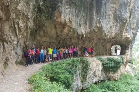 Grupo de excursionistas posa en la Ruta del Cares, superando la dificultad del terreno rocoso y los túneles.