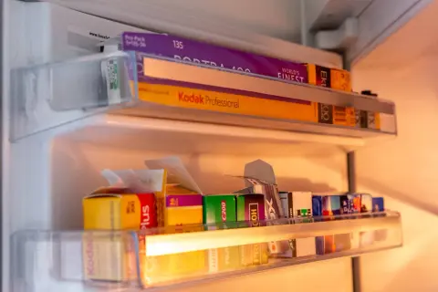 A collection of 35mm film rolls, including Kodak Portra 400 and Kodak Professional, stored in a refrigerator. These films are perfect for achieving that best 35mm film for vintage look.