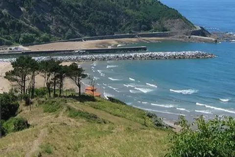 La playa mas cercana a Logroño, con olas rompiendo en la arena y un rompeolas protegiendo el puerto.