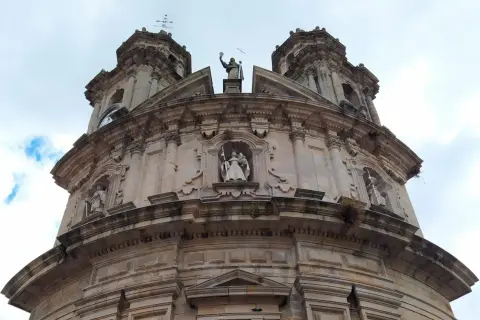 La imponente fachada de la iglesia de la Virgen Peregrina se alza bajo un cielo nublado, con sus torres y estatuas de piedra.