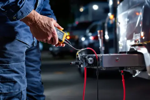 Vérification du retour de masse sur feux de remorque avec un multimètre. L'appareil indique 1.09V.